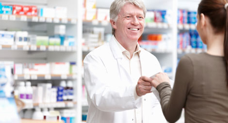 Male pharmacist issuing a prescription to a lady